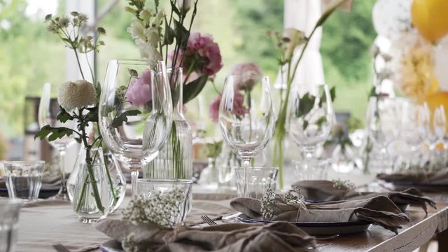 A rich luxury wedding with elements of dish decoration, golden plates, knives, forks, spoons, wine glasses and flowers.