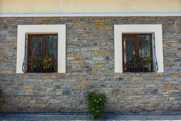 The wall of the old stone house with two windows