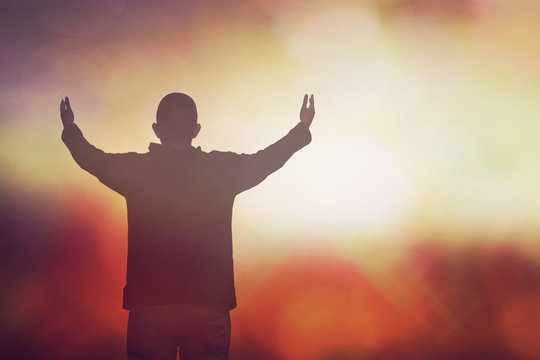 soft focus and Silhouettes of man raise hand up worship God over blurred  dark and light background,conceptual image of Christian concept of prayer and seeking God in the darkness of life.