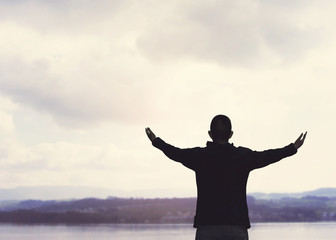 isolated of a man with widespread arms and hands against the cloudy sky and the lake  worship and thank God heavenly father, Christian worship concept