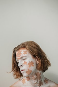 Portrait of a redhead mime artist with a floral design on his face