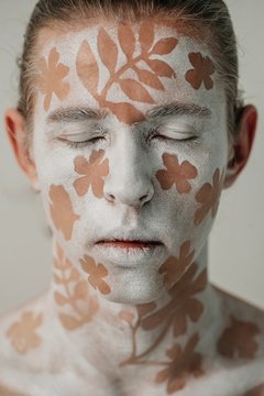 Portrait of a redhead mime artist with a floral design on his face