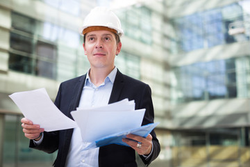 Smiling male architect in helmet with documents