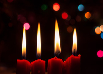  four red candles with Christmas decoration and dark background