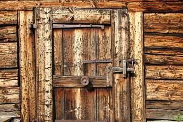 Alte rustikale und verwitterte Holztür von einem Bauernhaus auf einer Alm in den Tiroler Bergen