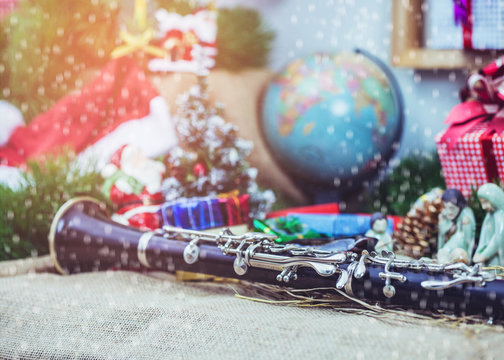close up of clarinet with blurred world globe , Christmas tree and decoration with gift boxes background, Snow falling in foreground