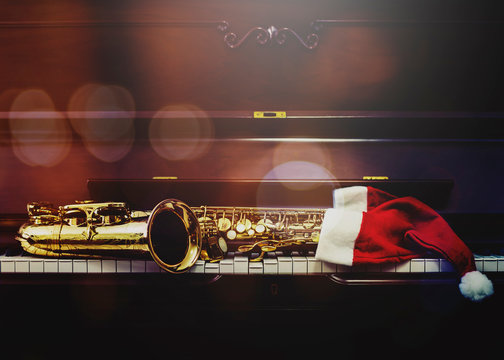 Saxophone with Santa clause hat on piano keys in the night, christmas background with copy space