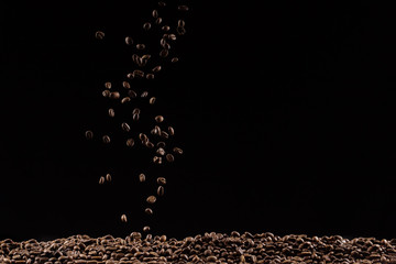 Coffee beans in the air flying in flight like a spray. On a black background, coffee shop...