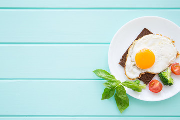 Tasty fried eggs with vegetables for breakfast on wooden table, top view, space for text. 