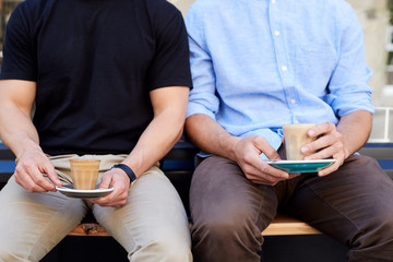 Close Up Of Two Men Sitting Outside Coffee Shop Drinking Coffee