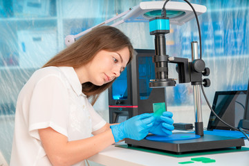 Woman worker in control of Resin LCD / DLP / SLA 3D Printer in technology lab