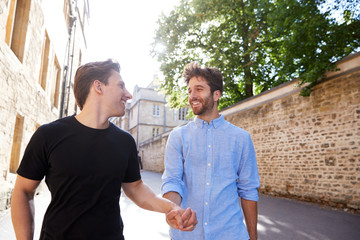 Loving Male Gay Couple On Vacation Holding Hands Walking Along City Street