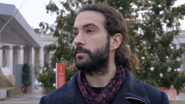 Attractive young man looking around in the city at christmas time