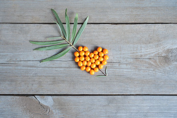 Orange sea buckthorn berry in arrow through heart shape on wooden table background 
