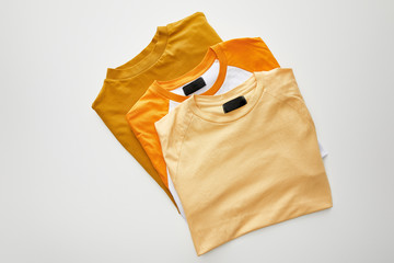 top view of color folded t-shirts on white background
