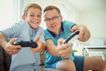 Happy young father and  his son playing computer games  with controllers very emotional