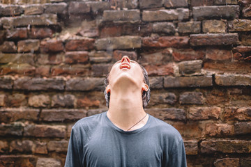 Desperate young man with mouth open looking up while standing in the rain