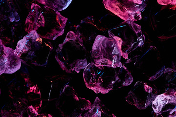 top view of transparent ice cubes with purple lighting isolated on black