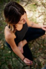 Top view of peaceful Caucasian woman in nature sitting on ground in lotus yoga pose and meditating. Summer time.