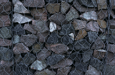 Texture of masonry, background of stone fenced with iron mesh.