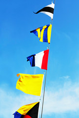 Marine signal flags on a mast against of the blue sky.