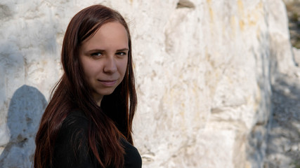 A beautiful young woman in black clothes against the white chalk mountains.