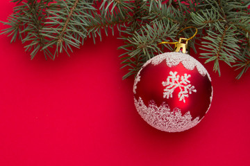 Christmas and New Year background. Colorful christmas composition with xmas tree branches and christmas balls. Christmas tree toy on a red background. Place for text.