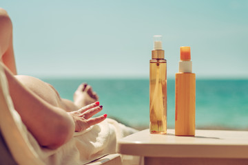 Girl is laying on sunbed at beach near two bottles of sunscreen. Suncare, skinprotection concept.