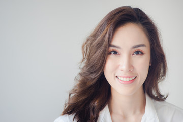 Fototapeta premium Indoor portrait of beautiful brunette young woman with smiling cheerfully, showing her white teeth to camera with copy space