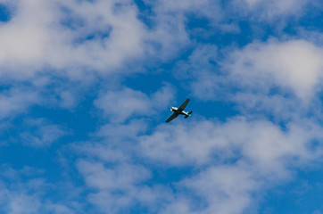 Small airplane flying in the sky with clouds