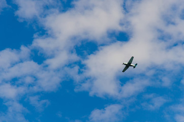 Small airplane flying in the sky with clouds