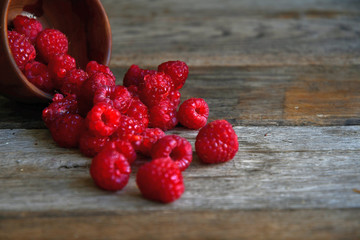 Tipped raspberries scattered on wooden boards from wooden utensils.