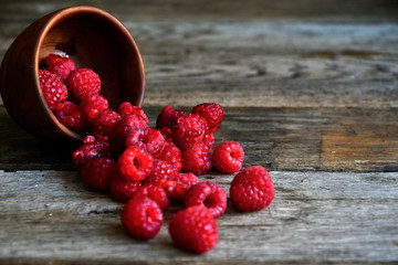 Tipped raspberries scattered on wooden boards from wooden utensils.