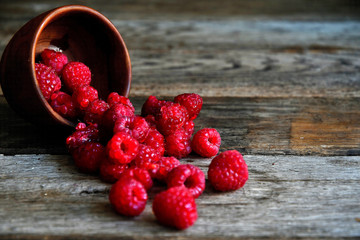 Tipped raspberries scattered on wooden boards from wooden utensils.