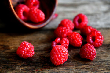 Tipped raspberries scattered on wooden boards from wooden utensils.