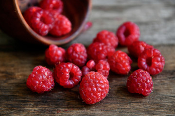 Tipped raspberries scattered on wooden boards from wooden utensils.