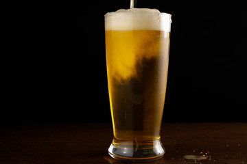 light beer is poured into a glass on a dark background