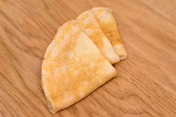 Three pancakes lying on a wooden table