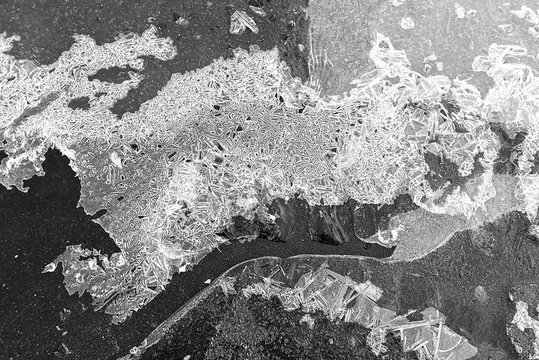 The texture of the ice crust on the pavement, black and white photo, background