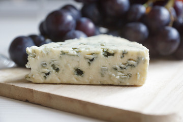Red wine in an elegant glass, cheese and a bunch of grapes.