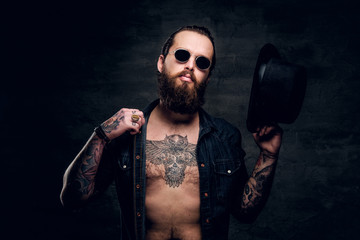 Portrait of brutal man with open denim shirt and tattooed chest.