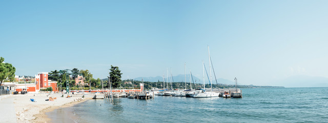 Padenghe del Garda, Italy - Sunday 1 September 2019: marina and bathers on the shores of Lake Garda on a sunny morning