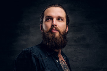 Handsome bearded man is posing for photographer at dark photo studio.