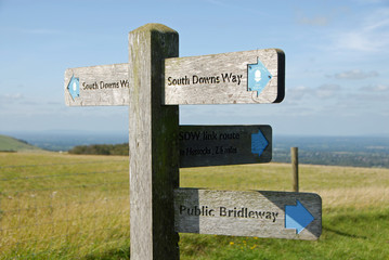 South Downs National Park, Sussex, England, UK. A signpost shows the route of the South Downs Way with views over the Sussex Weald. The South Downs Way is a national trail popular with walkers.