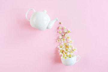 Creative layout of teapot and tea Cup with Jasmine flowers on a pink background. Jasmine tea.