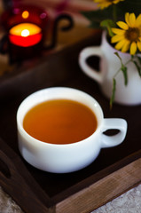 A cup of green tea and apples on the wooden trey on the table. Green tea in the white cup for breakfast. An autumn morning with green tea for breakfast in a cozy home.