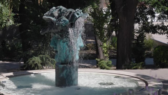 A fountain in the park in the form of a two-faced head.