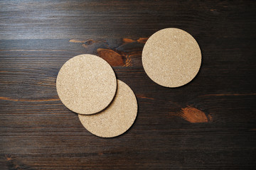 Blank cork beer coasters on wood table background. Flat lay.