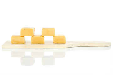 Group of five whole sweet golden caramel candy on small wooden cutting board isolated on white background