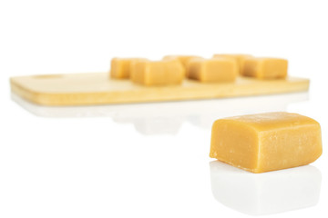 Group of seven whole sweet golden caramel candy on bamboo cutting board isolated on white background